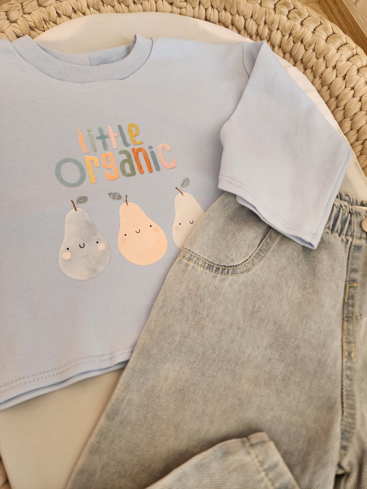 Children's organic cotton shirt with pear design and text on a woven surface
