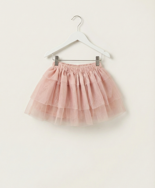 Pink tulle skirt on a hanger against a white background