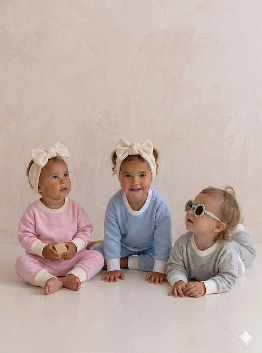 Three children wearing headbands and sitting on a light-colored floor.