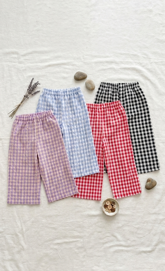 Four pairs of checkered pants in different patterns on a textured surface.