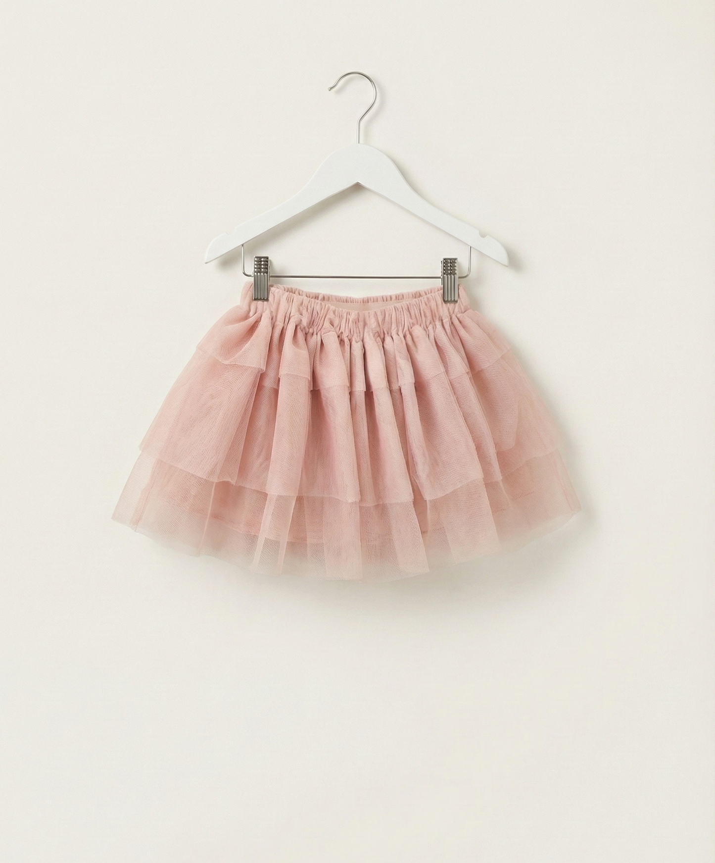Pink tulle skirt on a hanger against a white background
