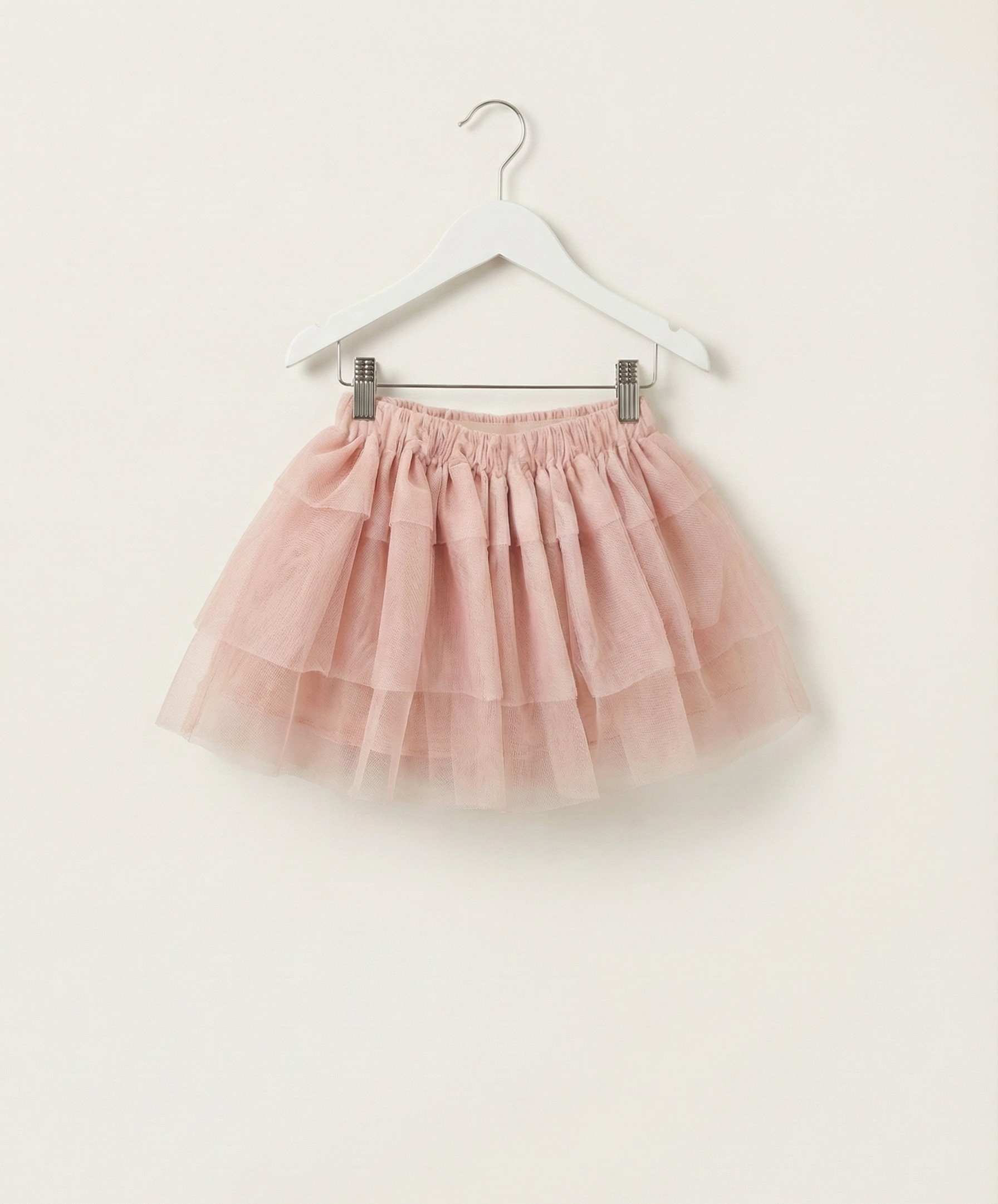Pink tulle skirt on a hanger against a white background